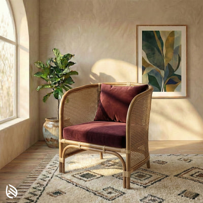 Wicker chair with red cushions in a sunlit room with a plant and artwork.
