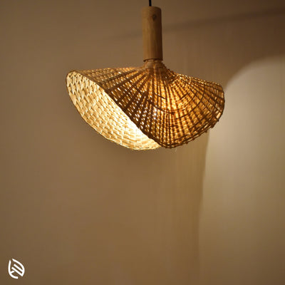 Handwoven bamboo wave pendant lamp glowing against wall - Japandi style