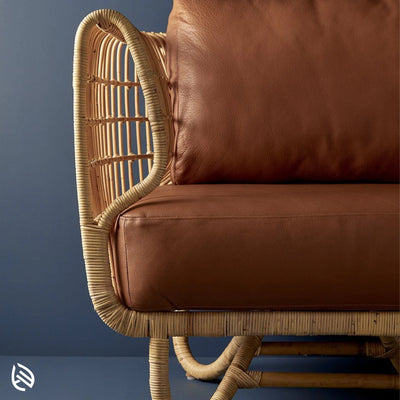 Close-up of curved natural rattan arm and brown leather cushion - detail of Curved Rattan Sofa Set craftsmanship.