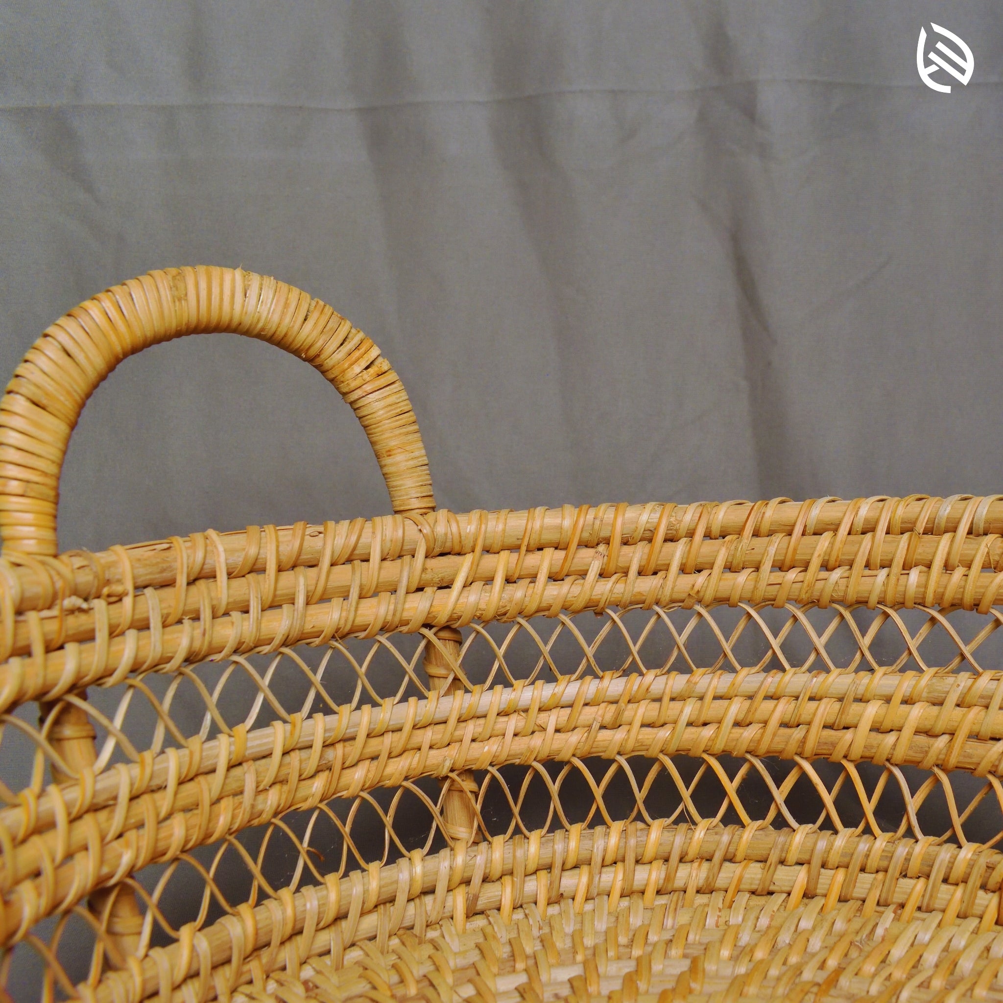Side detail of Drift Stash basket showing curved rattan handles and mesh weave