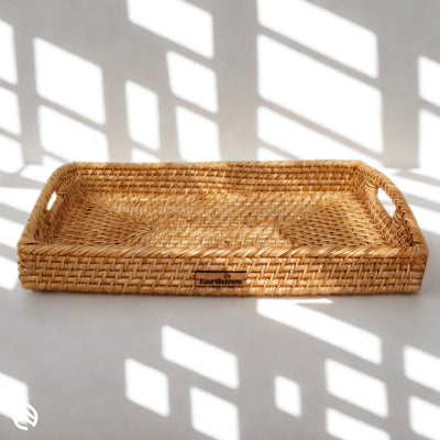 Handwoven rectangular rattan tray Nature Edge styled on tabletop with warm light