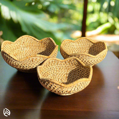 Woven rattan bowls set on wooden table outdoors