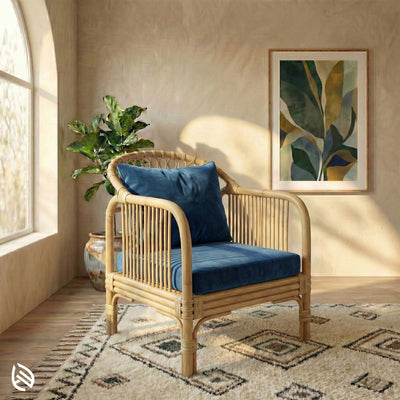 Rattan armchair with blue cushion in a sunlit room with a plant and artwork.
