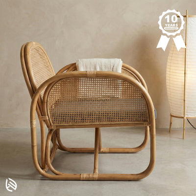 Wicker chair with a beige wall and lamp in the background