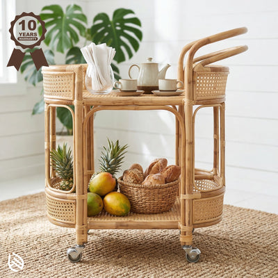 Wicker bar cart with fruit, bread, and tea set on a wooden floor.