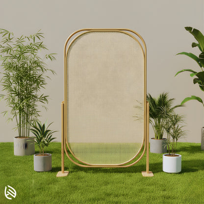 Freestanding oval rattan screen outdoors on grass with plants