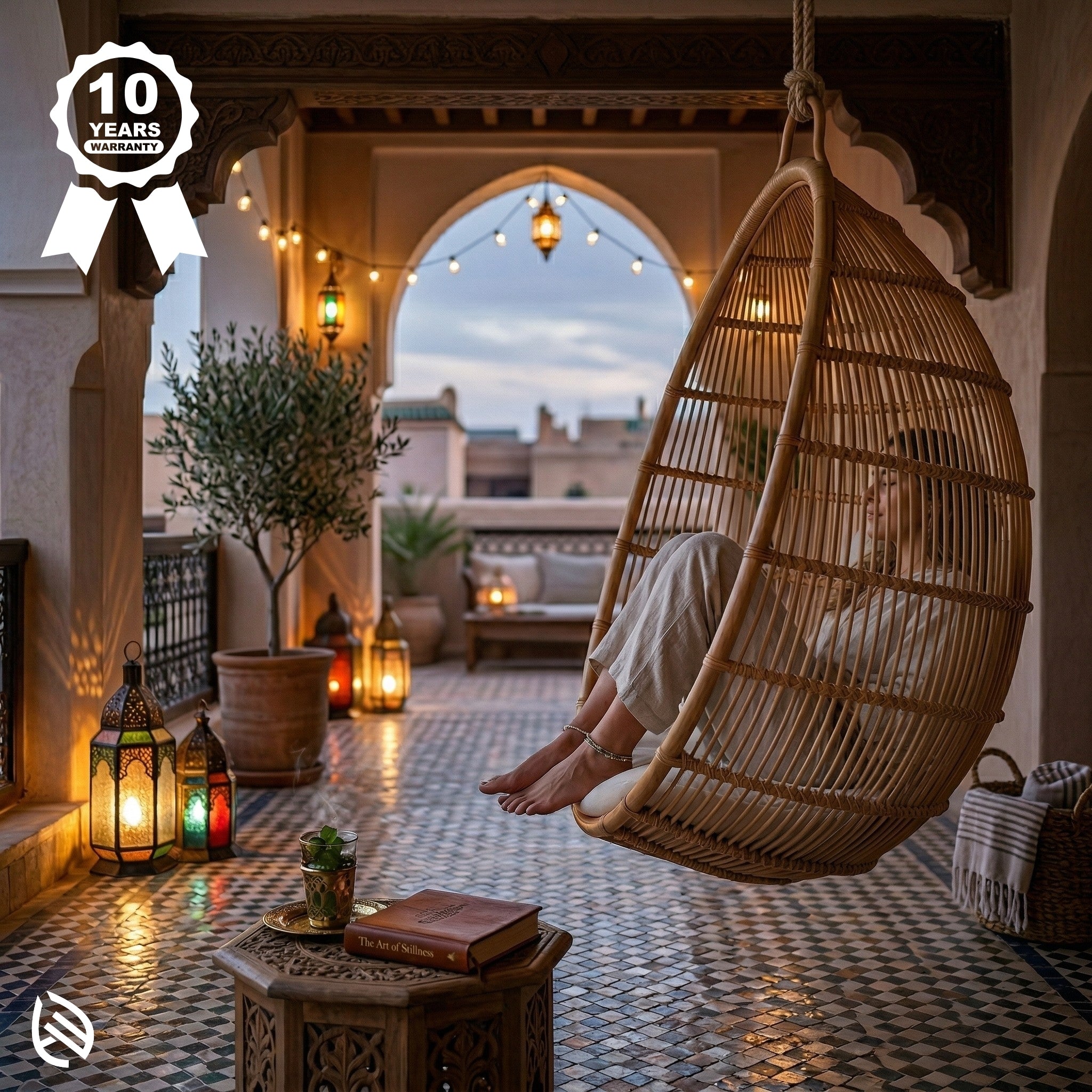 Person relaxing in a hanging woven chair on a cozy outdoor patio with lanterns and plants.